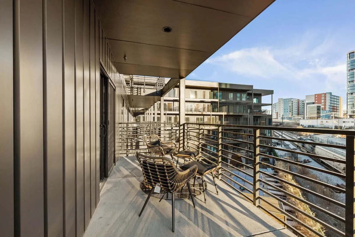 A balcony seating area with modern design elements, highlighted by a stunning cityscape in the background. The ambiance feels calm and sophisticated, ideal for enjoying a book or toasting the evening as city lights come alive.
