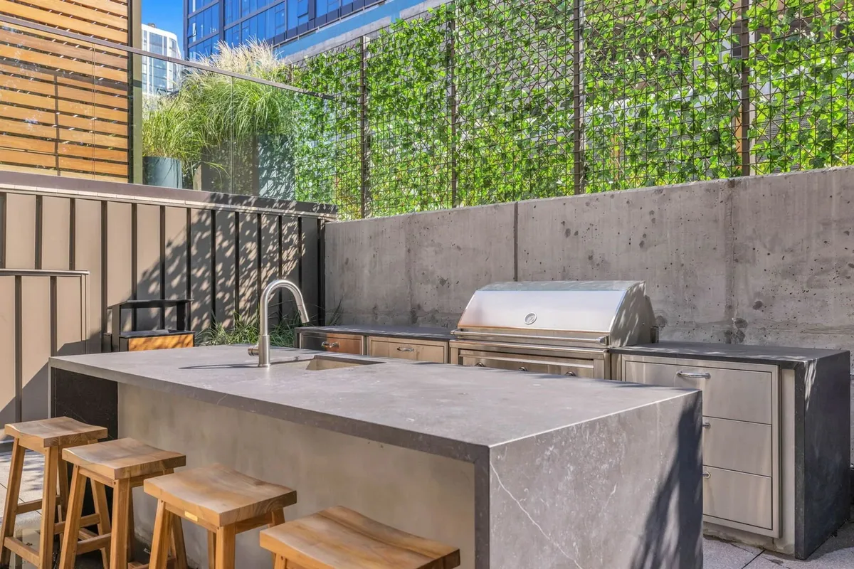 An outdoor kitchen and BBQ area featuring a built-in grill, bar stools, and a relaxed atmosphere. The setup is inviting for barbecues, social gatherings, and celebrating special occasions outdoors.