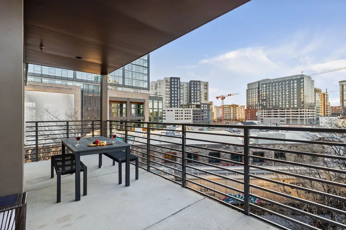 A stylish rooftop terrace with a dining table, railings, and breathtaking city skyline views. The space is ideal for al fresco dining, sunset gatherings, or simply relaxing while overlooking Nashville.