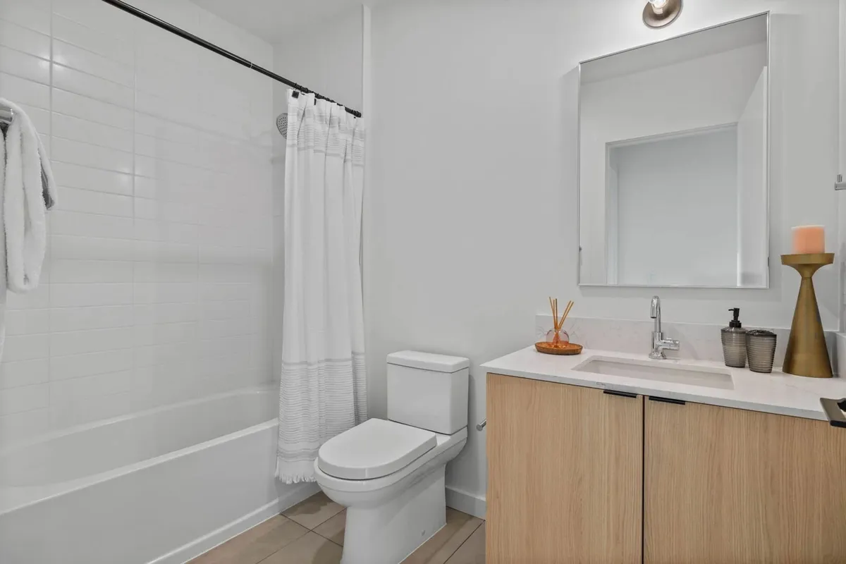 A modern bathroom featuring a sleek bathtub, a contemporary vanity, and a mirror that enhances the sense of space. The design is fresh and calming, invoking a spa-inspired atmosphere ideal for relaxation and self-care.